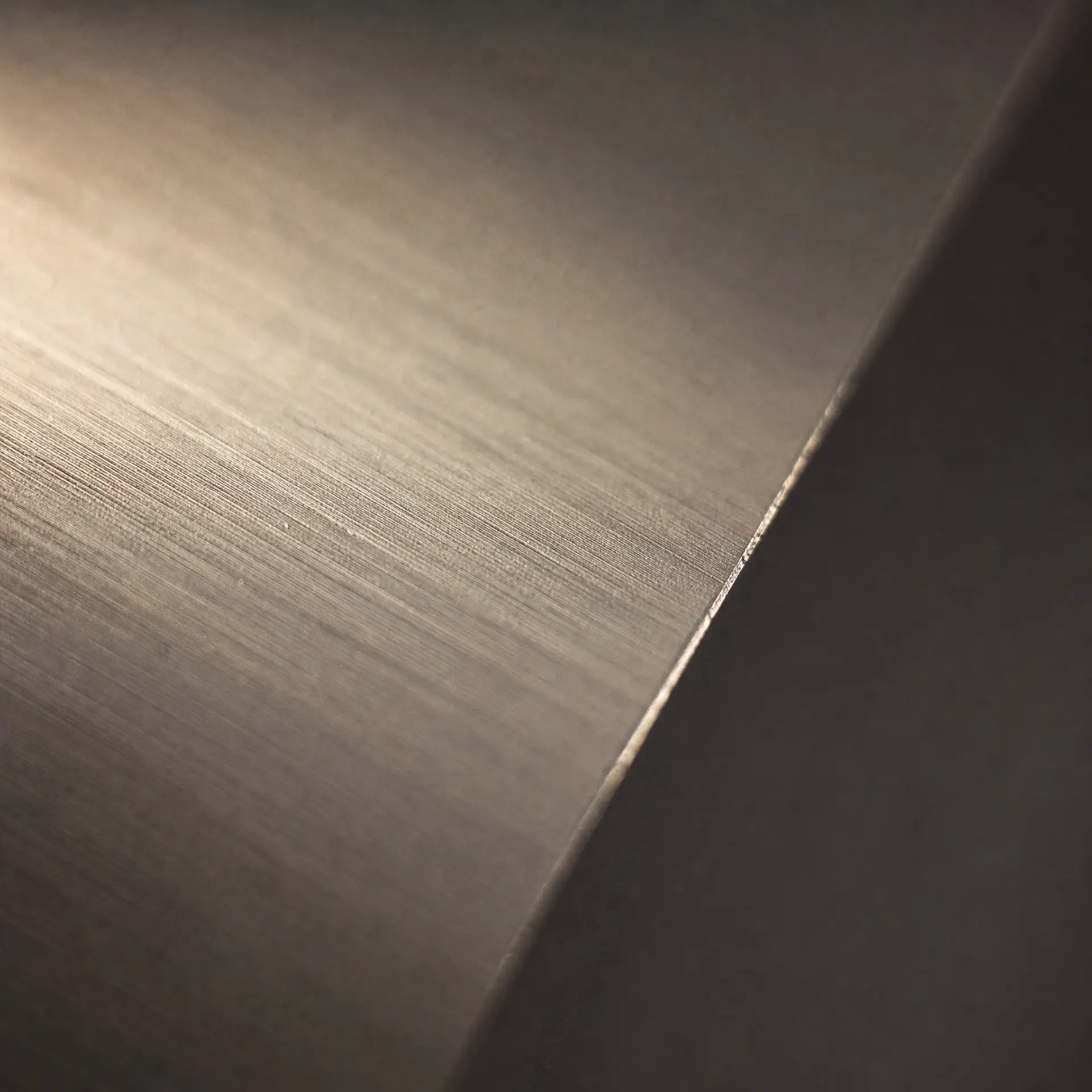 Brushed anodised aluminium surface, fine parallel grain caught by a raking light