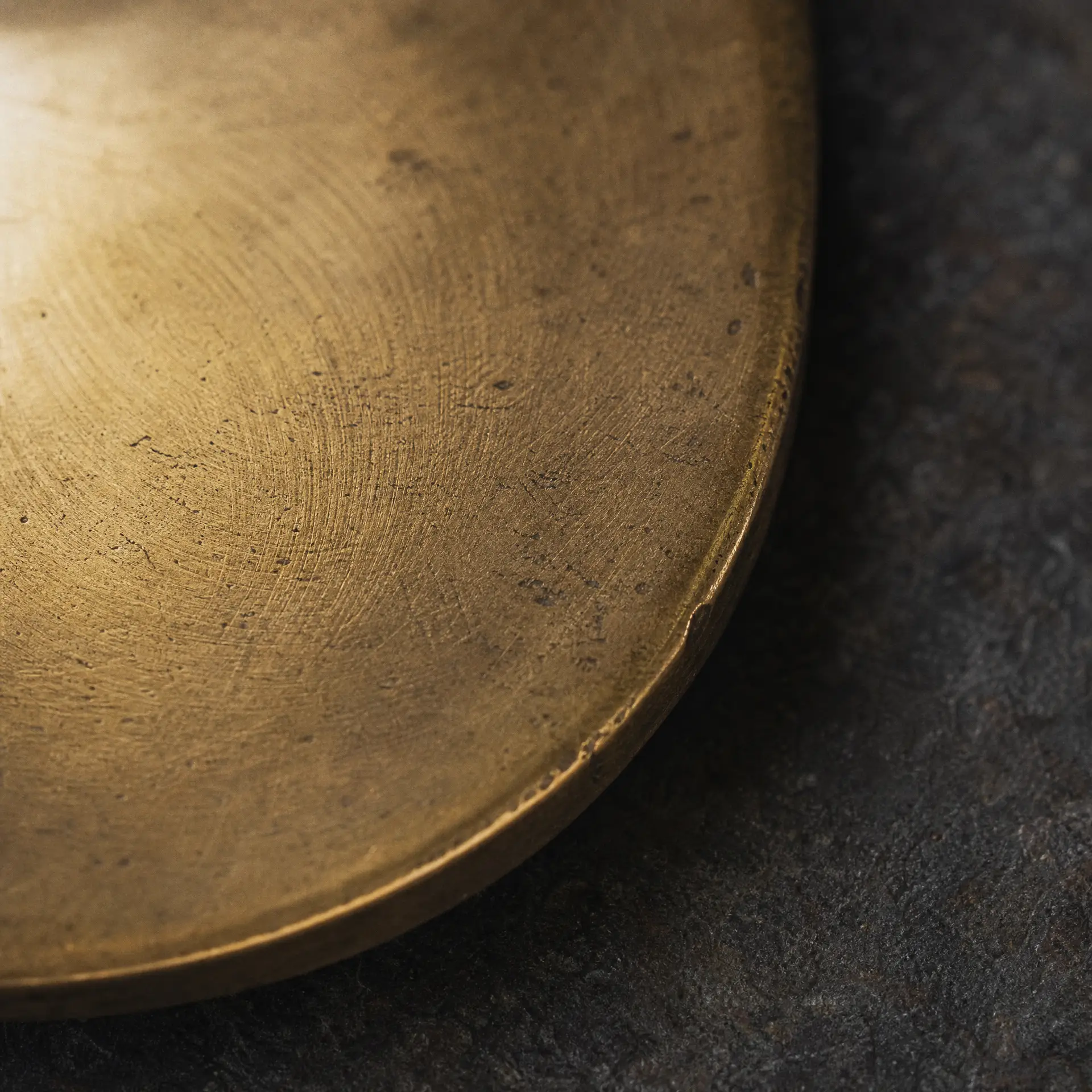 Brushed brass plate with a warm patina, circular brushing marks visible