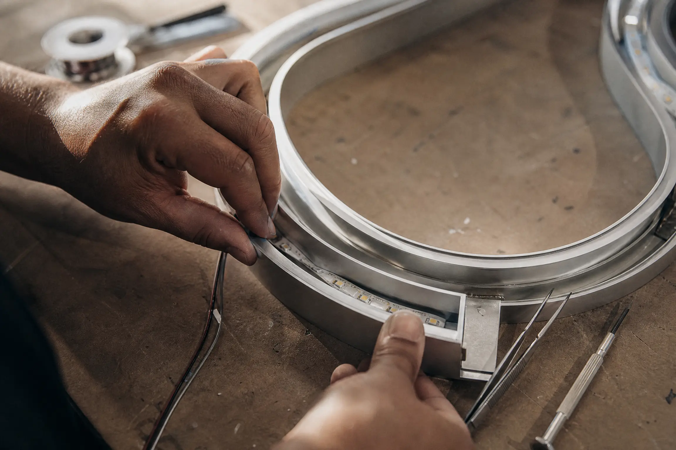 LED strip being fitted into the aluminium housing of a backlit built-up letter