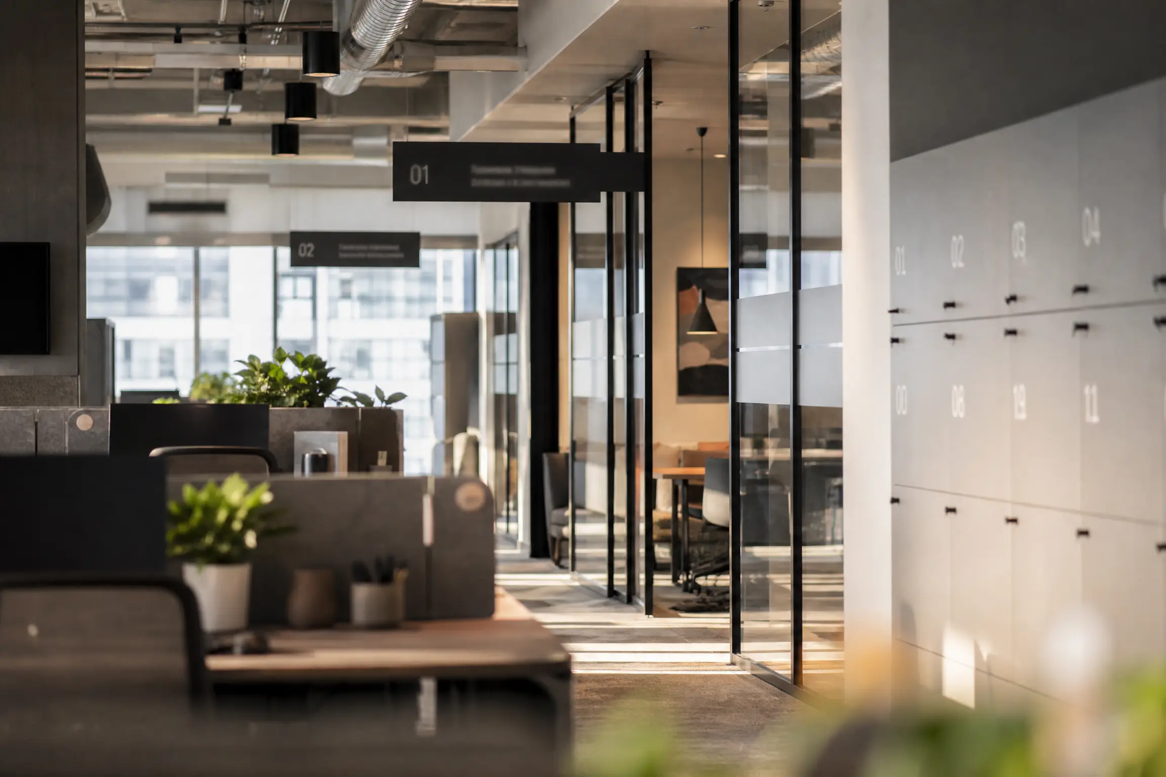 Plateau de bureaux en flex office, signalétique de zones suspendue et bandes de confidentialité sur cloisons vitrées